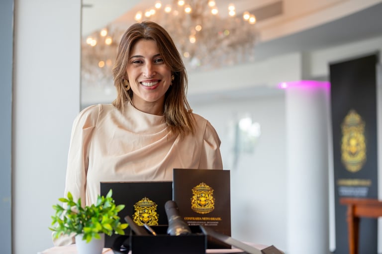 Smiling woman in beige shirt at counter with black product boxes featuring gold logos and green plant