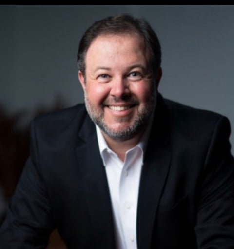 Igor Moya, business strategist and growth advisor wearing black blazer and white shirt against gray background