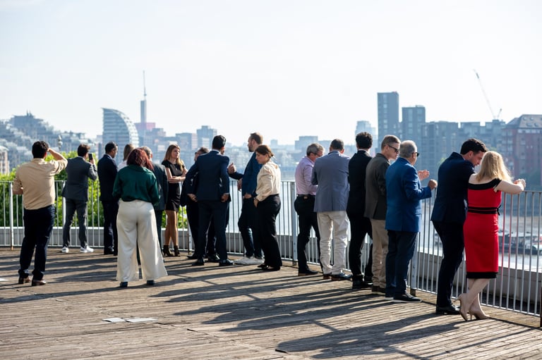 Group of people standing on an outdoor observation deck with a city skyline in the background