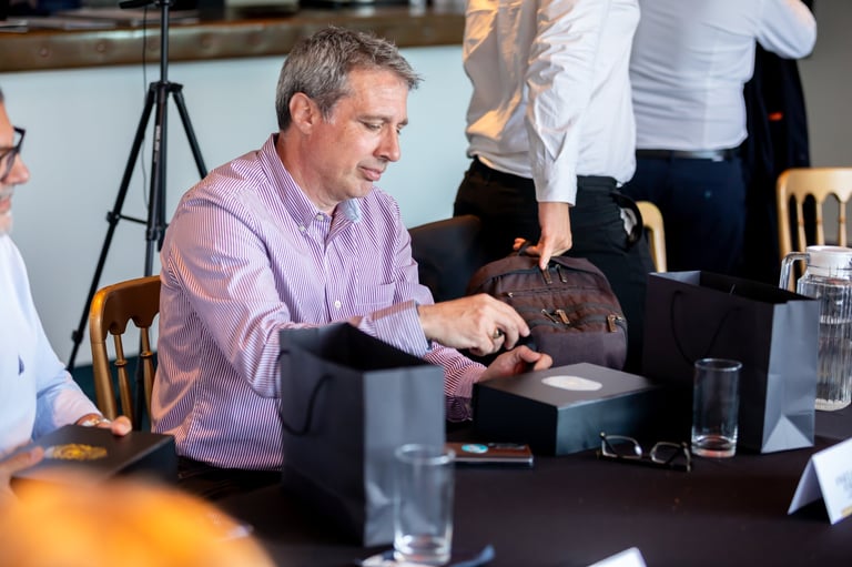 Man in purple shirt at conference table holding brown leather wallet during business meeting