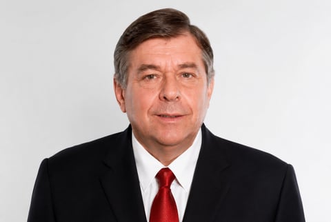 Portrait of Dr. Nicolau Esteves, senior strategic advisor and education entrepreneur, wearing a black suit jacket and red tie against a white background