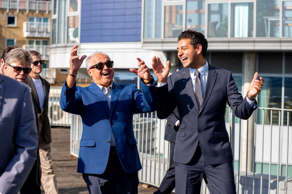 Group of businessmen in suits celebrating outdoors on a rooftop with modern buildings in the background