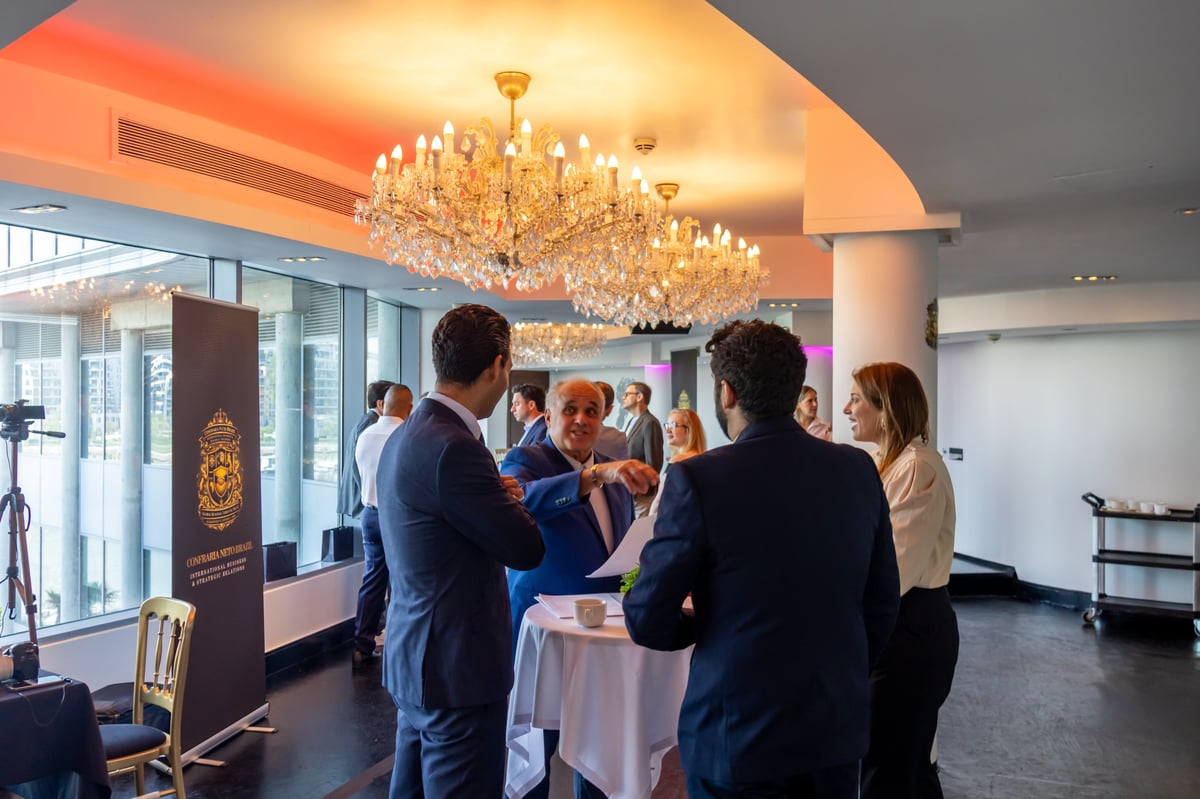 Business professionals mingling at a formal indoor networking event under a crystal chandelier with warm ambient lighting