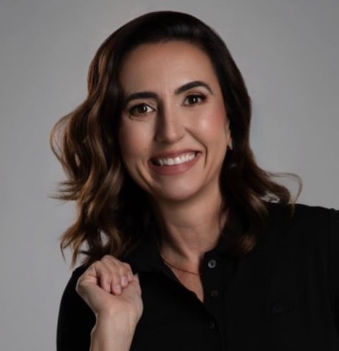 Carol Moya, Brazilian-American business strategist and LinkedIn specialist wearing black blazer against gray background