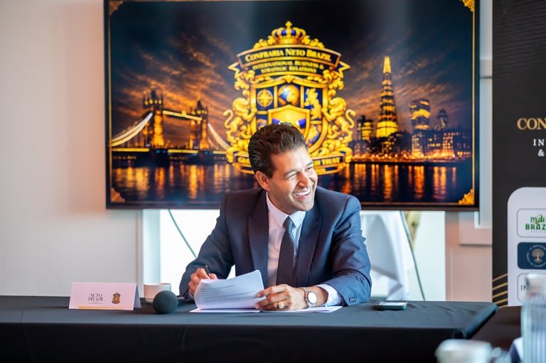 Man in business suit seated at desk with London skyline artwork and illuminated landmark images displayed on wall behind him
