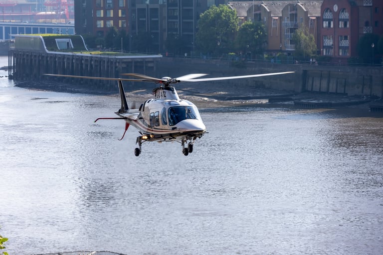 Helicopter hovering over a city river with historic buildings in the background