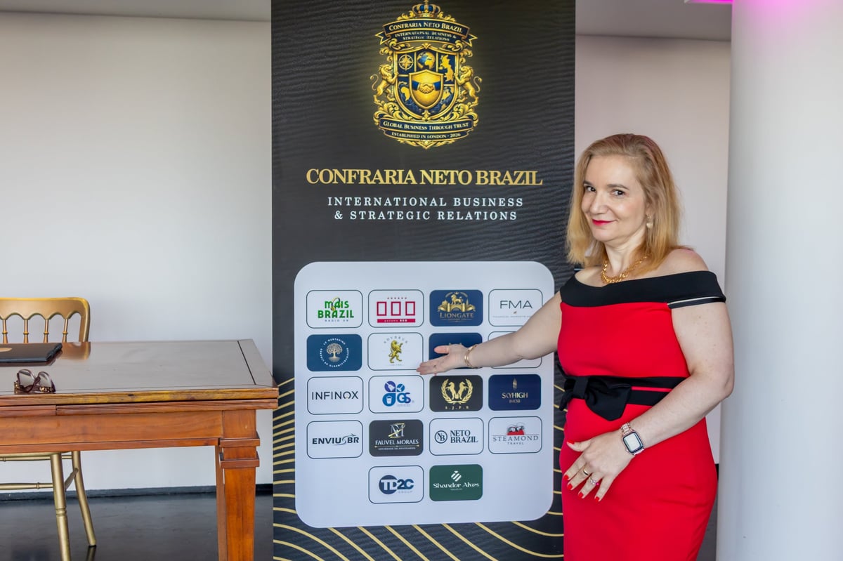Woman in red and black dress standing next to display board showing logos at Confraria Neto Brazil office