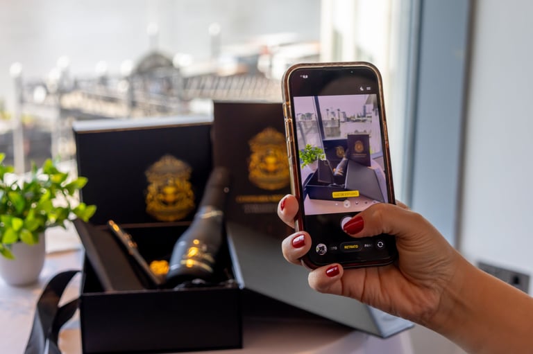 Person holding smartphone photographing Buddha figurines in a black gift box near a window with city view