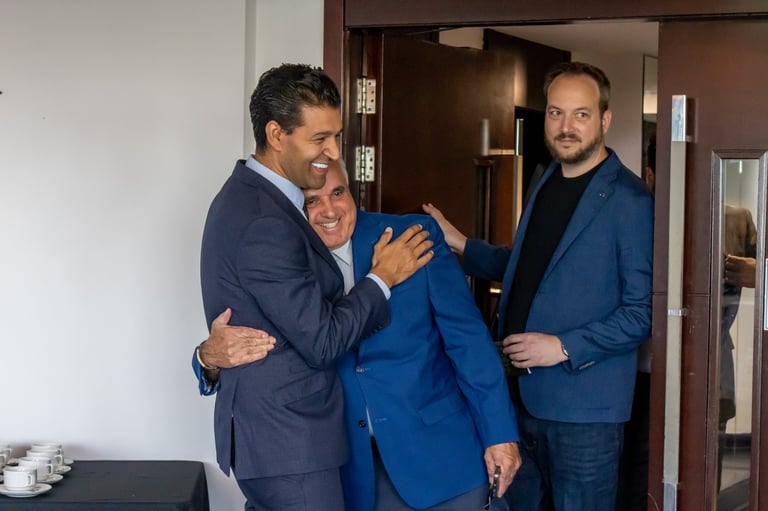Three men in business suits having a friendly conversation in an office hallway
